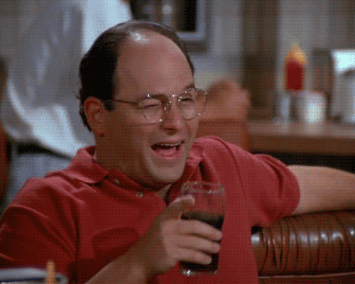 Animated clip of a man in a red polo shirt at a diner booth, laughing and winking as he raises a glass.